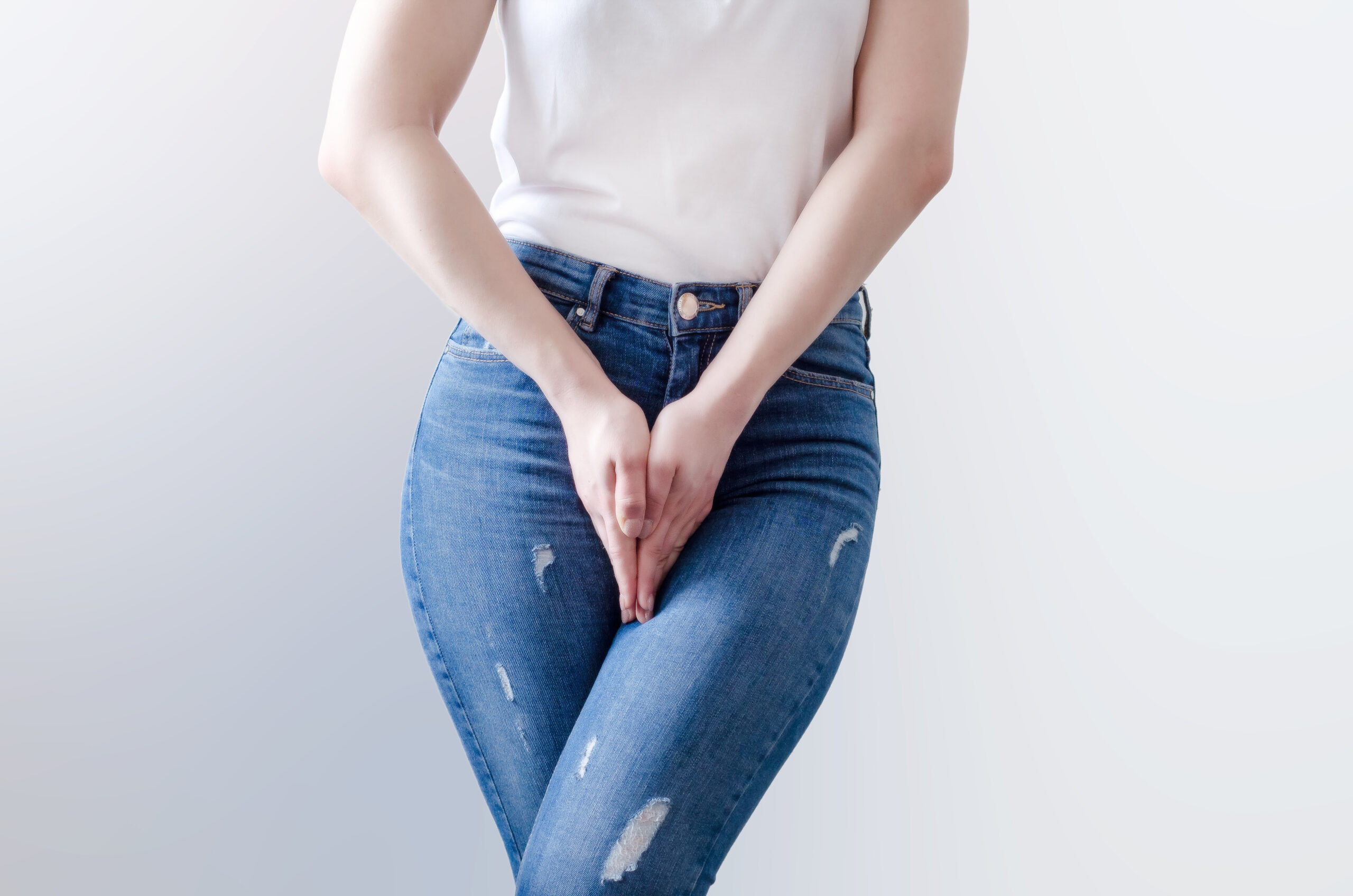 Young woman in jeans standing with her hands between legs
